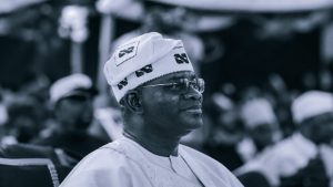 File image of wearing white traditional attire, a patterned cap and rimless glasses, photographed in three-quarter profile.